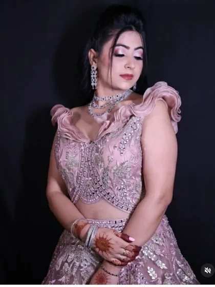 A model posing in the dusty pink engagement gown, her hands framing her face to show off the intricate details of the bodice.