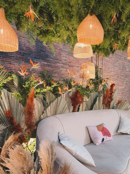 The bride wanted a boho and chic theme that complemented the venue's brick wall. We used a mix of pampas grass, dried palm leaves, and exotic bird of paradise flowers, all softly lit by hanging cane lanterns to create this warm, nature-inspired seating area.