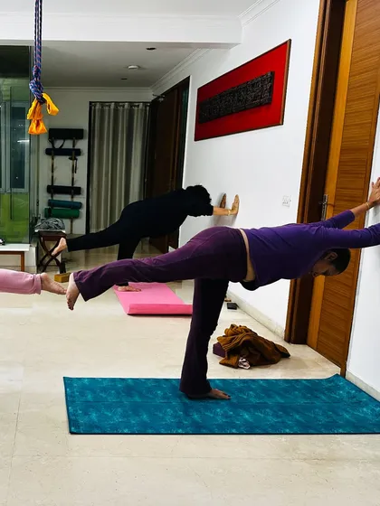 In this supported Virabhadrasana III (Warrior III), the wall helps the student find stability. This allows her to focus on lengthening her spine and engaging her core, bringing her fully into the present moment.