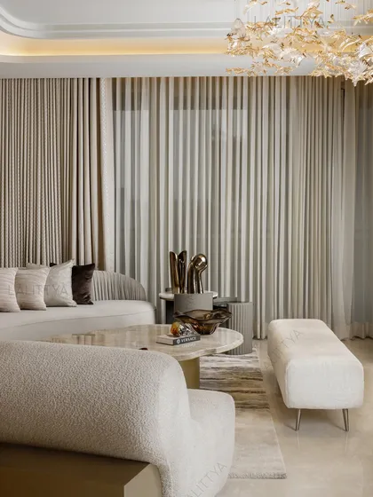 A moment of calm in a bustling living area. This shot captures the soft textures of the bouclé armchair and tufted sofa, the gentle curves of the furniture, and the warm glow from the sculptural chandelier above.
