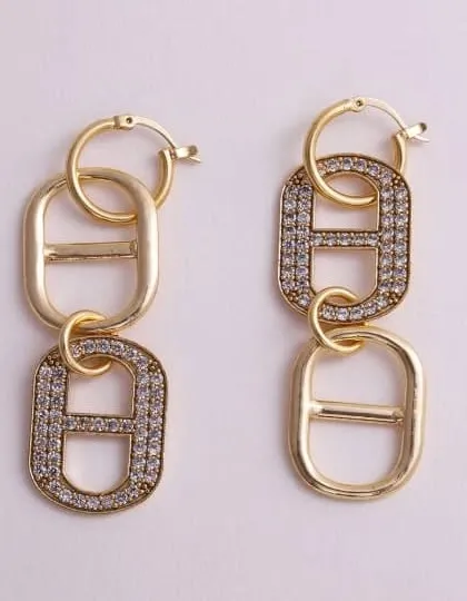 A detailed photograph of gold-tone chain link earrings, with one link fully encrusted with sparkling crystals, showcasing a mix of textures.