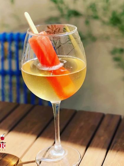 A fun and refreshing way to enjoy a drink. This wine spritzer is served with a fruit popsicle, which melts to add more flavor.