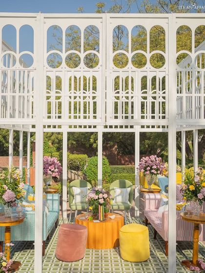 White trellis structures create elegant, open-air 'rooms' for lounging, furnished with colorful and comfortable seating.