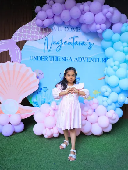 The birthday girl makes a heart sign with her hands, showing her love for her "Under the Sea Adventure" party.