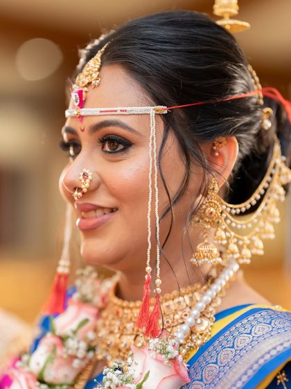 A side profile showcasing the traditional Maharashtrian jewelry and flawless makeup.