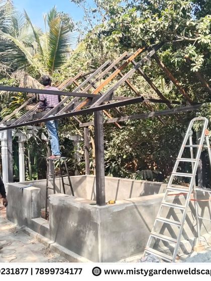A wide shot of the cow shed construction site. The project is taking shape within the lush green environment of the farm, designed to be both functional and harmonious with its surroundings.