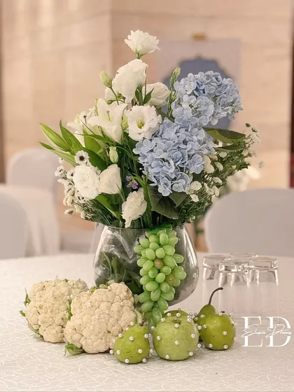 Another angle of the unique centerpiece, highlighting the unusual but beautiful combination of cauliflower, pearl-studded fruits, and fresh flowers.
