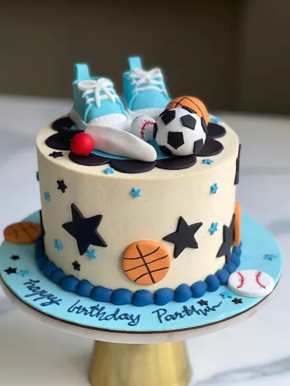 A fun sports-themed cake for a birthday boy. This buttercream cake is decorated with fondant basketballs, soccer balls, and baseballs, and topped with a pair of handmade fondant sneakers.