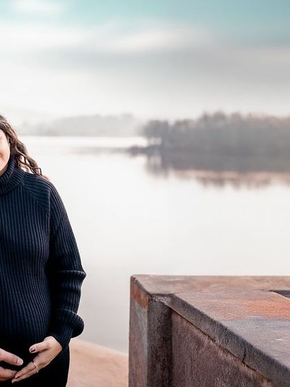 An intimate embrace by the lake. This photo captures the quiet, protective love between partners as they await their baby's arrival.