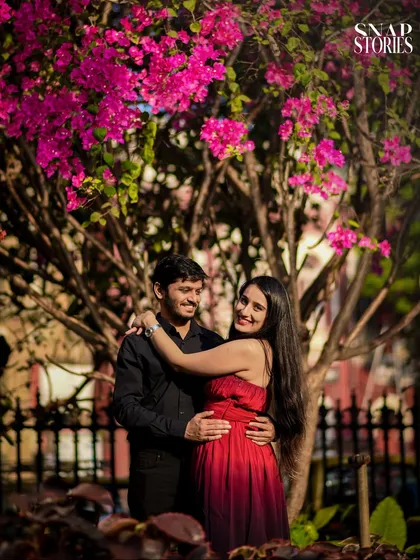A vibrant portrait of a couple framed by beautiful pink bougainvillea flowers, adding a pop of color and natural beauty to their pre-wedding shoot.