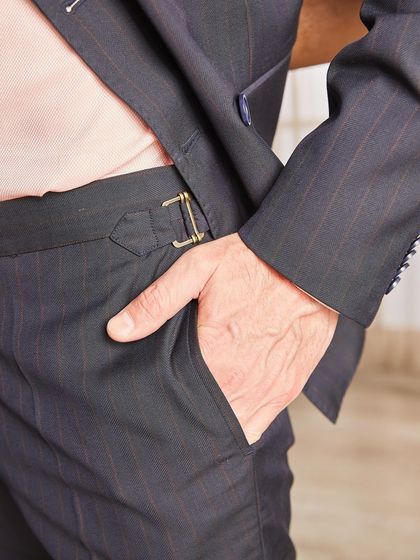 A detail shot of the trousers from a pinstripe suit, featuring a classic side-adjuster buckle. This is a traditional bespoke detail that offers a cleaner look than belt loops.