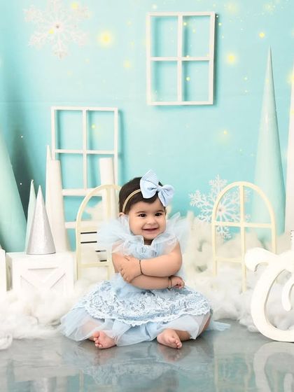A winter wonderland is the perfect setting for a first birthday portrait. Dressed in blue, she looks like a little snow princess in this magical setup.