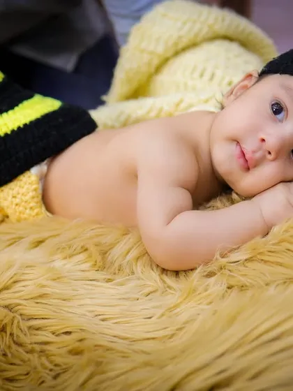 A close-up of our adorable honeybee baby, awake and looking at the camera with big, curious eyes. The hand-knitted costume is soft and perfect for newborns.