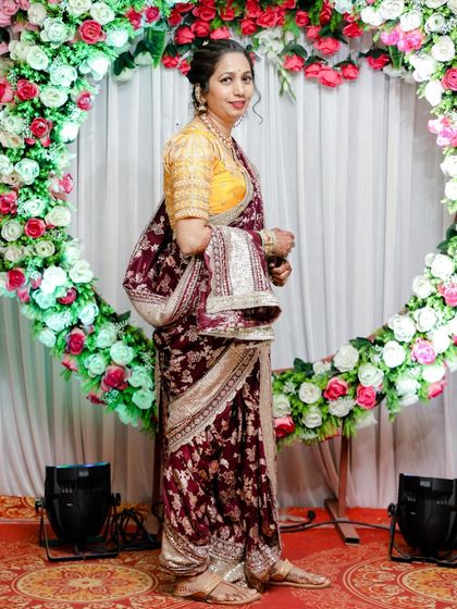 A beautiful client in a maroon floral Nauvari, posing gracefully at a wedding event.