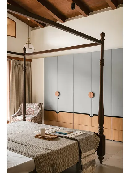 These bespoke wardrobes blend a soft, powdery grey with warm oak. The oversized circular wooden pulls act as modern Kolam-inspired strokes, adding a graphic and tactile detail to the minimalist design.