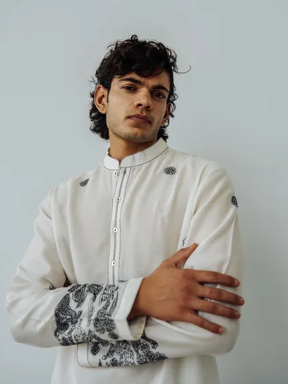 A portrait for the Wabi Sabi menswear lookbook. The three-quarter shot highlights the detailed embroidery on the cuffs of the white kurta.