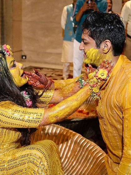 The fun and messy joy of a Haldi ceremony. The backdrop of bright yellow drapes and marigold flowers enhances the traditional feel of this happy occasion.