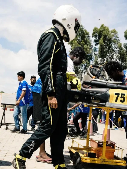 A driver walks next to his kart on a trolley.