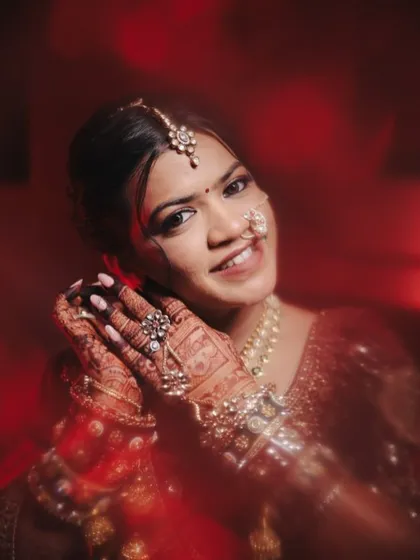 A beautiful close-up showing the intricate details of the bride's henna and jewelry. Her makeup is kept soft and glowing to complement the rich, traditional elements of her look.