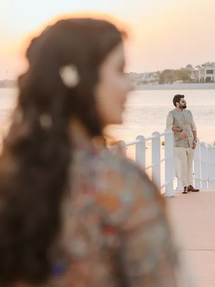 A creative shot of the groom in focus on a pier, with the bride artfully blurred in the foreground.