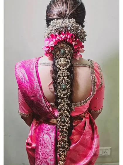 A closer look at a traditional South Indian bridal hairstyle. This intricate braid, known as a jada, is adorned with fresh flowers and elaborate hair jewelry, creating a truly grand and timeless look for the main ceremony.