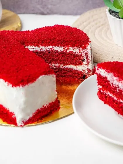 A red velvet heart cake with a slice placed separately on a plate, showing the cake's layers and texture. This is an effective way to show both the whole cake and a single serving.