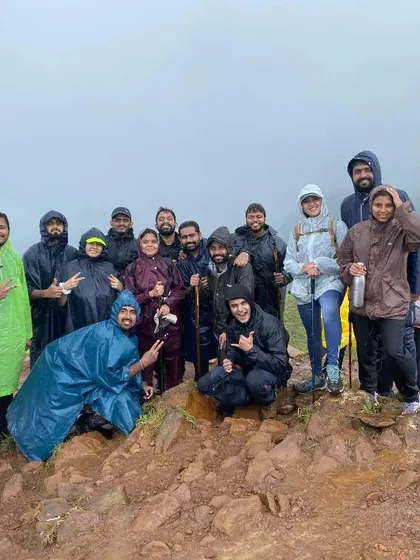 A group of trekkers in ponchos, smiling and posing on a muddy trail. We embrace all weather and find joy in every moment of the adventure.