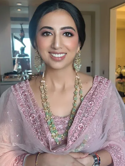 A close-up of a happy client ready for a wedding celebration. We focused on a soft pink monochromatic makeup look to harmonize with her pastel pink outfit, creating a fresh, dewy, and timeless appearance.