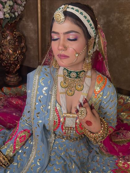 A close-up on the jewellery for the blue lehenga look. The combination of a green beaded choker with a long white beaded necklace adds layers of texture and color, complementing the outfit's embroidery.