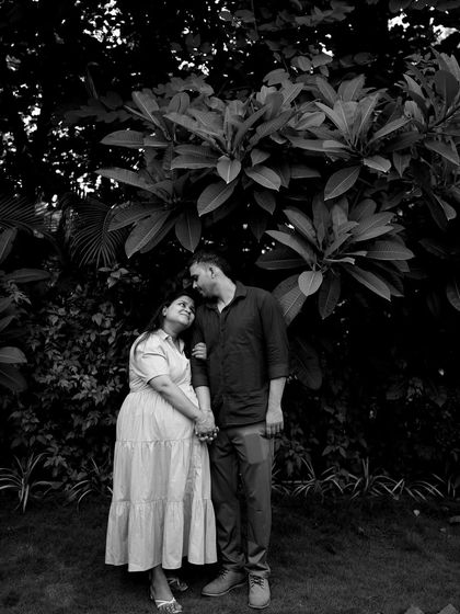 A beautiful black and white portrait of the couple standing under a large tree. The dramatic lighting and their loving gaze create a timeless and romantic image.