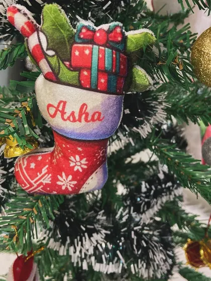A personalised Christmas stocking ornament, filled with mini gifts, hanging on the tree.