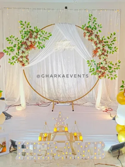A blessed first birthday with a baby Ganesha theme. The elegant setup features a white and gold color scheme, a circular arch with draping and florals, and adorable Ganesha cutouts.