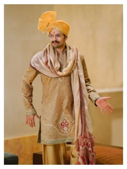 A welcoming gesture from the groom. This candid portrait captures his warm personality and the intricate embroidery on his traditional wedding kurta.