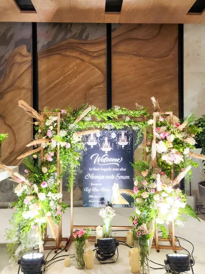 This rustic-chic welcome sign is framed with a mix of pampas grass, fresh greenery, and pastel flowers, creating a warm and inviting entrance.