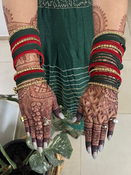 The beautiful, dark stain from a Karwa Chauth mehendi, pictured here with traditional bangles. The color is deep and even, highlighting every intricate detail.