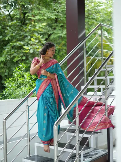 A stunning shot of a client in a traditional blue and pink Nauvari saree, rented from my collection. This photo was taken on the staircase at our partner farm studio, using the natural light and green surroundings.