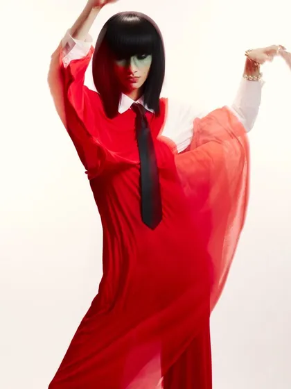 Full shot of the green makeup and bob wig look, showing how the makeup and hair work with the flowing red outfit to create a dynamic, high-contrast fashion image.