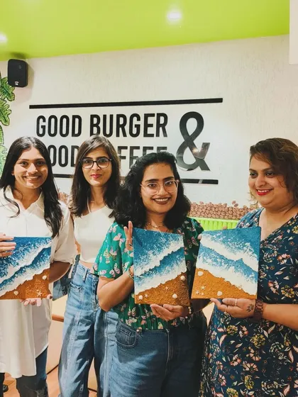 A group of four women in Indore proudly hold up their beach-themed texture paintings. A perfect weekend activity with friends.