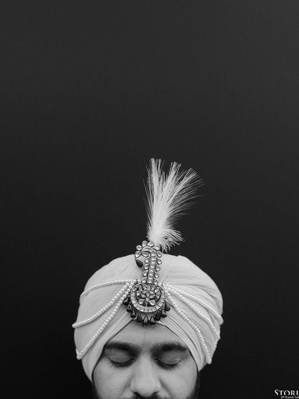 A minimalist black and white portrait focusing on the groom's turban (safa), highlighting a key element of his wedding attire.