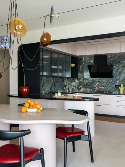 A glimpse into a residential project where the goal was to be bold, eccentric, and fun. This open-plan kitchen and dining area uses a dramatic marble backsplash, fluted glass, and a custom-designed, free-flowing dining island to create a space that is as impactful as a piece of art.