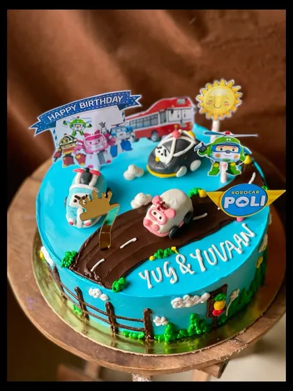 A Robocar Poli themed cake for a young fan. The design includes a road, grass, and various character toppers to create a playful scene.