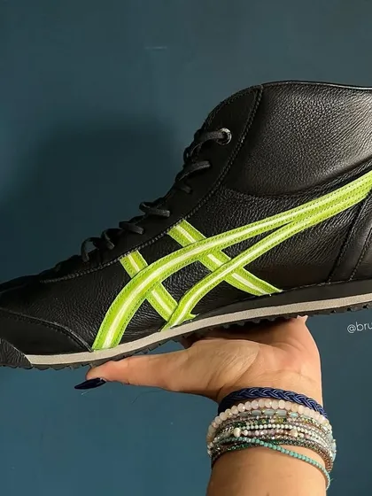 A custom pair of black Onitsuka Tiger high-tops with a clean, neon green stripe design.