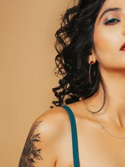 This shot frames the model's shoulder, highlighting her floral tattoo and the delicate necklace, combining beauty with personal style.