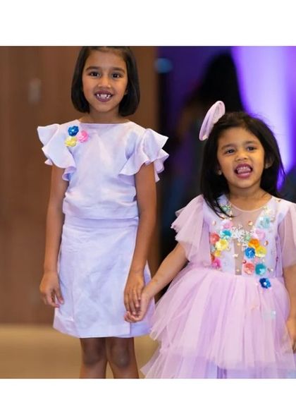 Two sisters, two beautiful lilac dresses. On the right, our "Charm" dress with its full tulle skirt, and on the left, a simpler coordinated dress with flutter sleeves for the older sister.