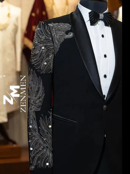A close-up of the silver hand embellishment on the black tuxedo. The feather or wing-like design is crafted with sequins and beads for a multi-dimensional, sparkling effect.