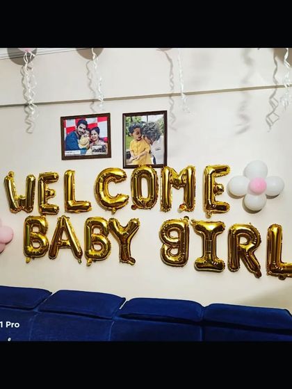 A 'Welcome Baby Girl' balloon decoration on a wall, complete with family photos, adding a personal touch to the celebration.