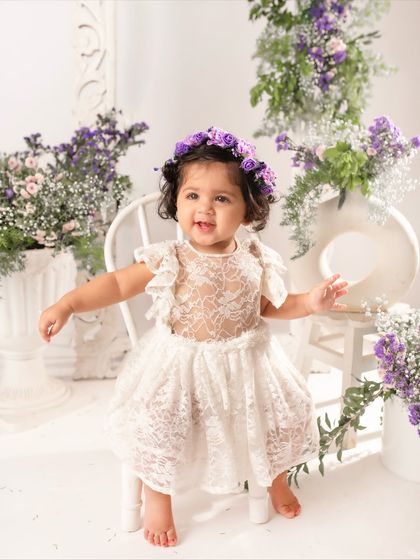 A happy dance from the birthday girl. She looks so joyful in her lace dress and purple flower crown, celebrating her first birthday in style.