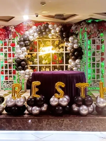 A stylish Boss Baby themed stage decoration with black and silver balloons and marquee letters.