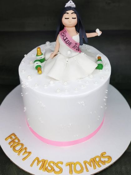 A "From Miss to Mrs" cake for a bride-to-be. This tall chocolate hazelnut cake features a fun fondant topper of the bride celebrating with champagne.