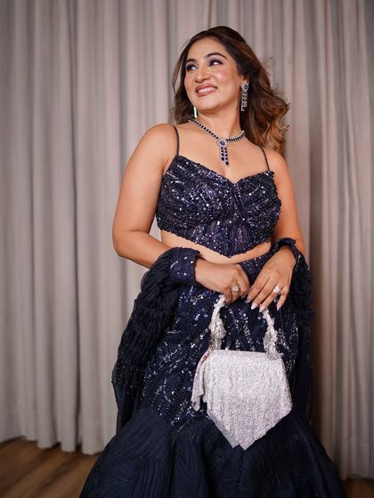 The complete look, showcasing how the sparkling clutch and soft hair waves balance the drama of the sequined lehenga. Styling is about creating harmony between all the elements of your outfit.